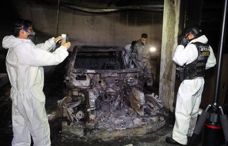 Investigators check the scene of a fire that started when a parked Mercedes-Benz electric vehicle ignited at an apartment complex in Incheon, Friday. Yonhap